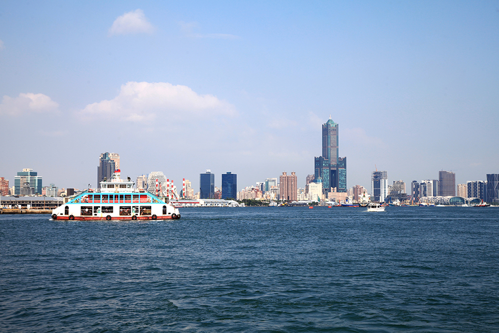 站在愛河西岸拍照，將愛河東岸的85大樓及高樓林立的都會景色收入鏡頭裡。