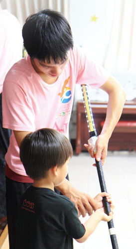 Touring members teach how to grasp LED-lit sticks at Yongan Children\'s Home