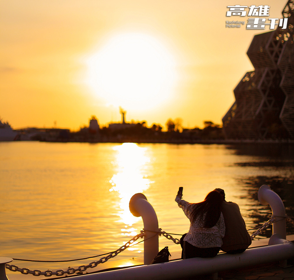 夕陽映照港灣水面，人們在河岸邊留影停留，為高雄的日常時刻添上一抹溫柔光景。(攝影/Carter)