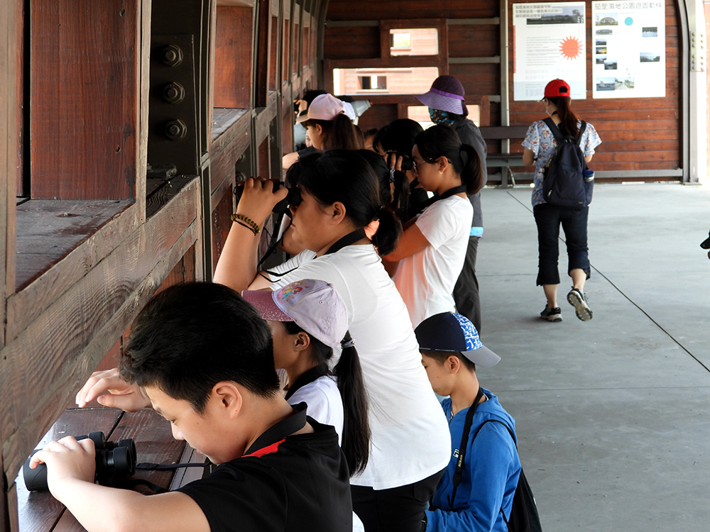 孩子們拿著望遠鏡，在賞鳥亭裡觀水鳥、聽解說。（圖片提供/高雄市茄萣區觀光發展協會）