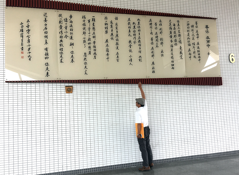 位於禮堂外牆巨幅的詩壁，呈現由名書法家薛平南書寫余光中的詩-等你 在雨中。