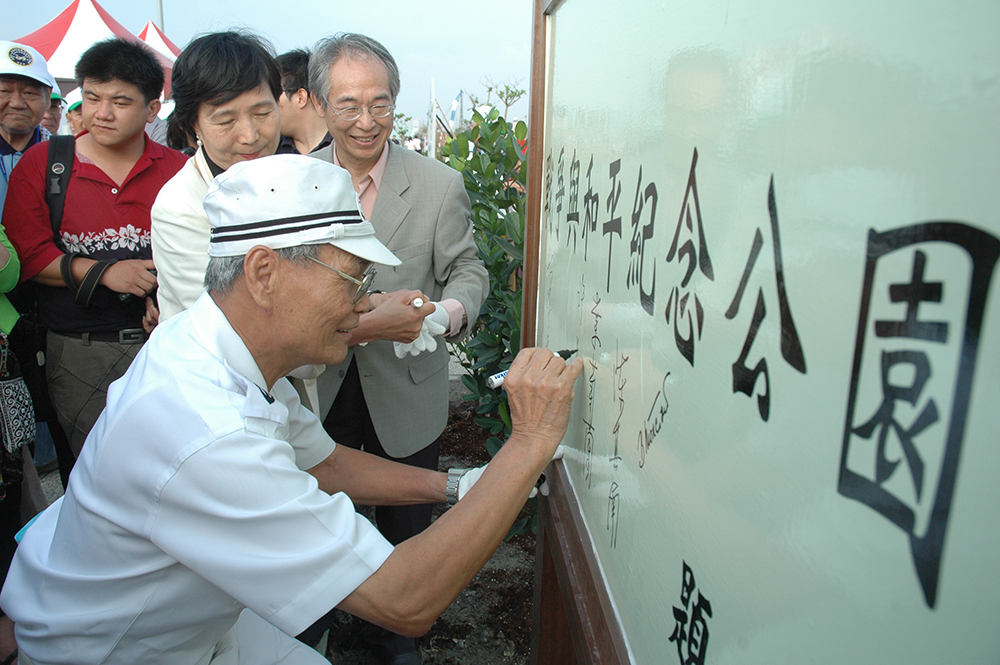 穿著日軍水手服的許昭榮在「戰爭與和平紀念公園」植樹活動中簽名。