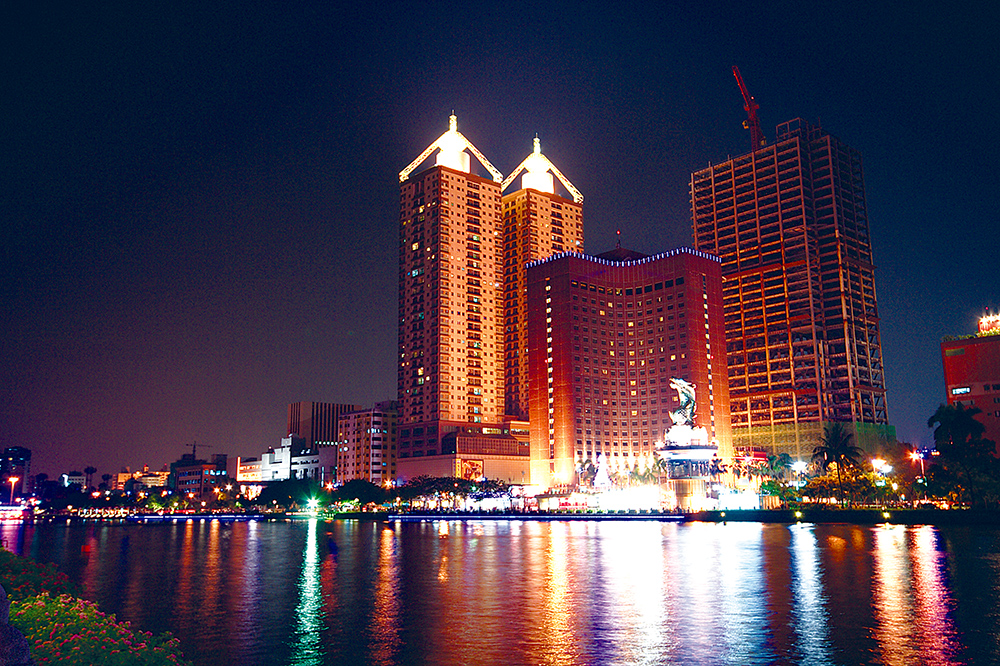 愛河旁的飯店·高樓夜晚大放光芒·正與鰲燈相輝映。