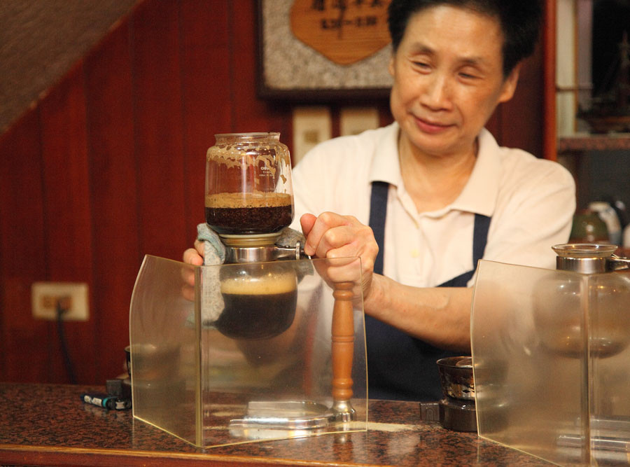 小堤咖啡的顏二姐正在小堤吧檯上沖著咖啡。（攝影/Hally Chen）