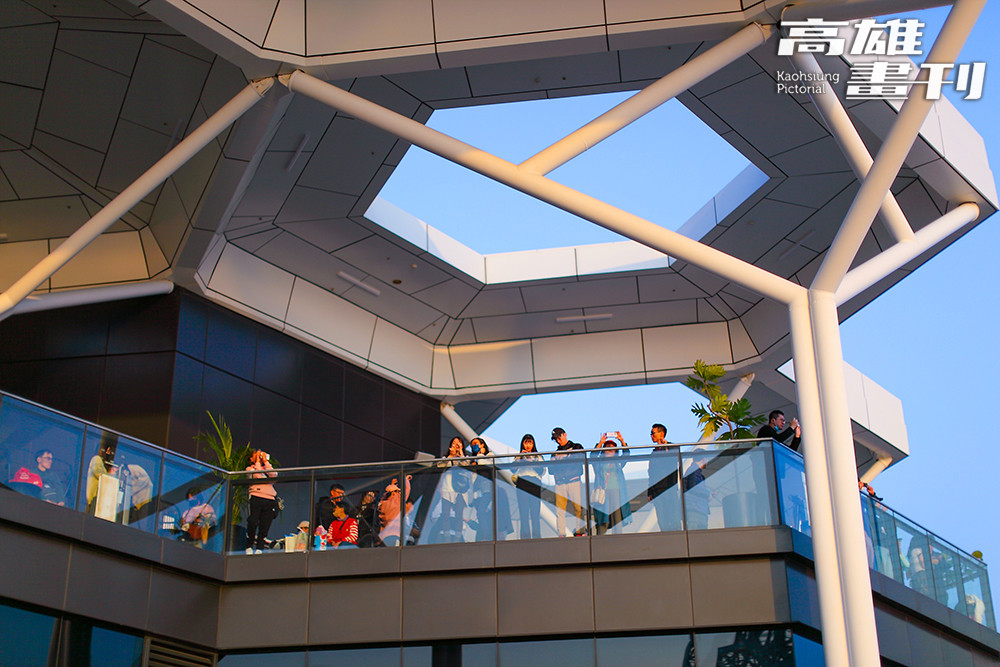 夕陽映照港灣水面，人們在河岸邊留影停留，為高雄的日常時刻添上一抹溫柔光景。